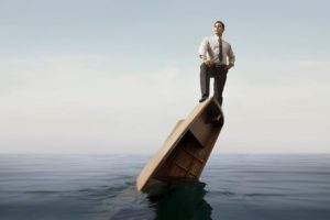 man in dress shirt and tie standing victoriously on top of a sinking canoe