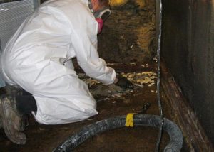AQUIS technician in white hazmat suit removing non-compliant coating and debris from aging air handler